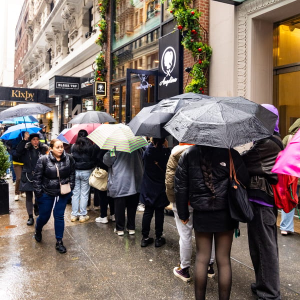 Customers lined up under umbrellas outside Angelina Bakery in the rain