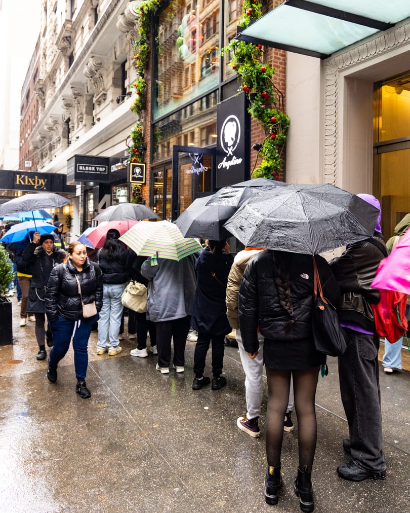 Customers lined up under umbrellas outside Angelina Bakery in the rain