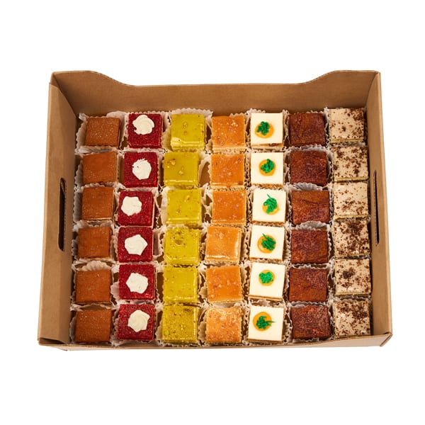 A catering box of assorted mini cakes and petit fours in a rainbow of colors and flavors.
