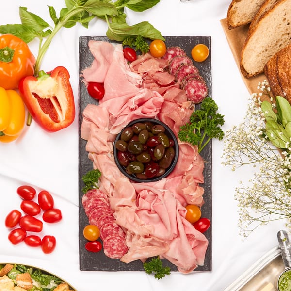 Overhead view of a buffet spread with charcuterie, salads, bread, and Caprese skewers.