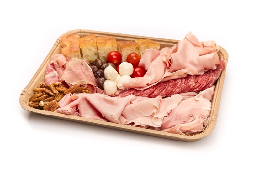 A charcuterie board with various meats, cheeses, olives, tomatoes, pecans, and focaccia bread.