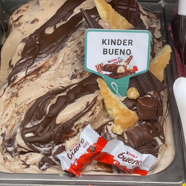 Kinder Bueno gelato topped with chocolate drizzle, sponge, chocolate bars, and Kinder Bueno candies.