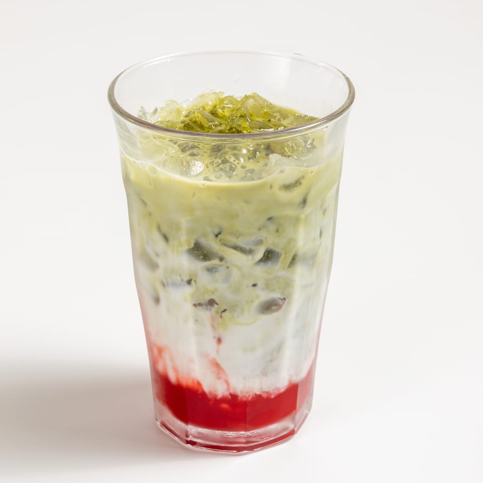 Iced matcha latte with strawberry syrup and milk, served in a tall glass.