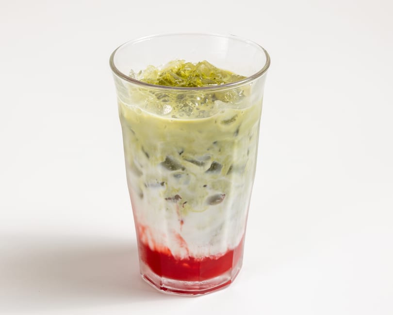 Iced matcha latte with strawberry syrup and milk, served in a tall glass.
