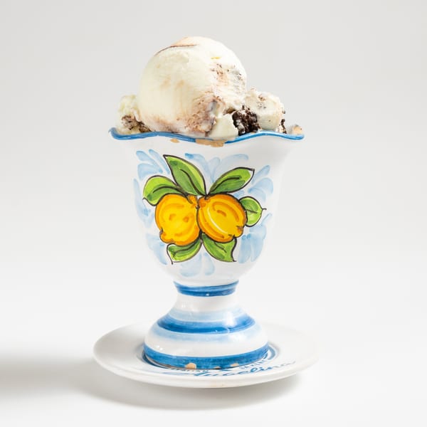 Cookies and cream gelato in a decorative white, blue, and yellow cup on a white background.