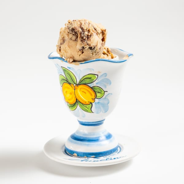 Scoop of chocolate swirl ice cream in a decorative white, blue, and yellow cup.