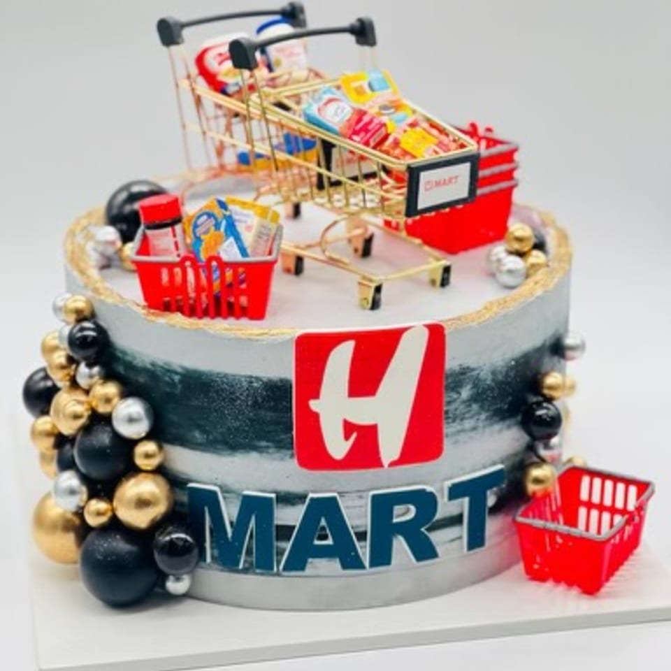 A round H Mart themed cake with miniature shopping carts and groceries on top.