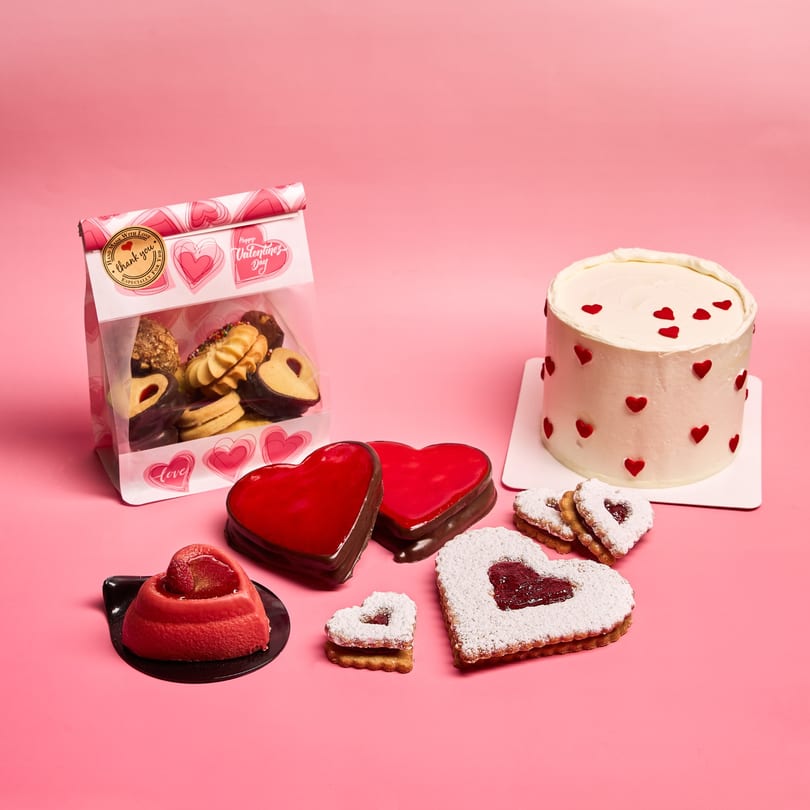 Valentine's Day desserts including a cake with red hearts, heart-shaped cookies, and chocolate-dipped treats.