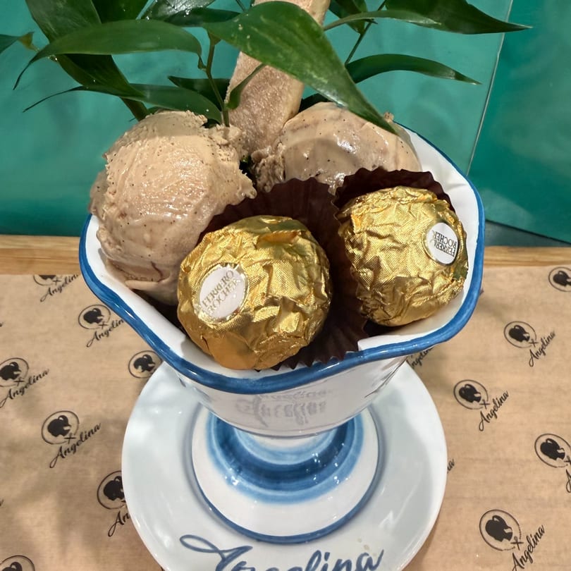 Three scoops of ice cream with two Ferrero Rocher chocolates in a white and blue bowl.