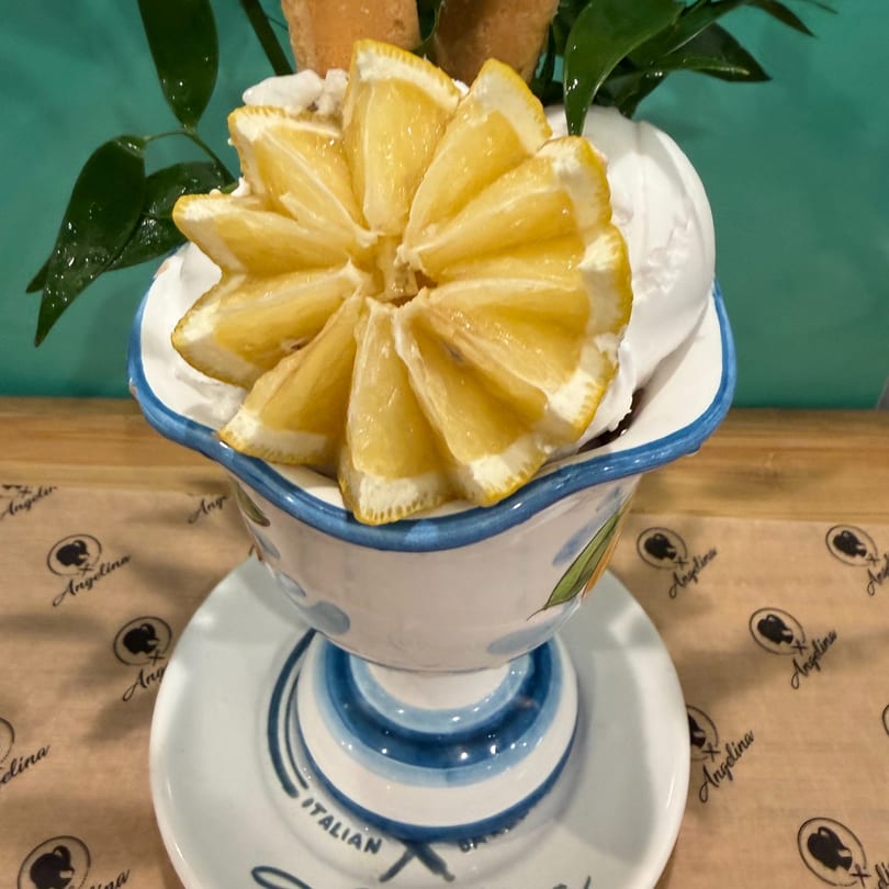 Lemon sorbet dessert in a decorative bowl, garnished with lemon slices and green leaves.